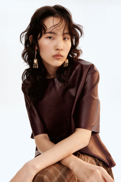 Modern Muse flower shaped gold dangle earrings styled with autumn textures