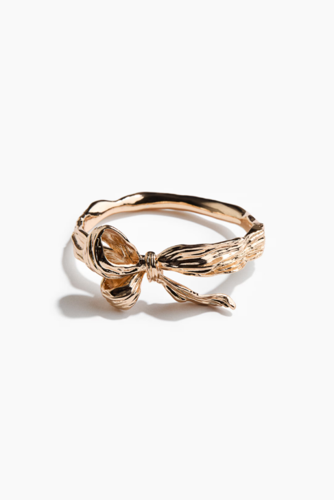 Gold bow shaped hinged bangle styled for the Winter Elegance Edit look