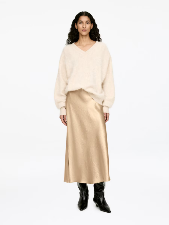 Fluid satin midi skirt adding movement to a winter white outfit
