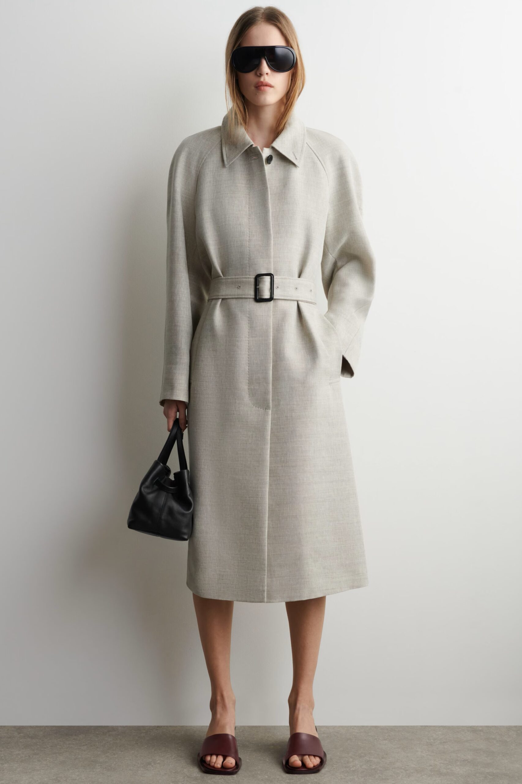 Long trench coat layered over a dress in a modest luxe look